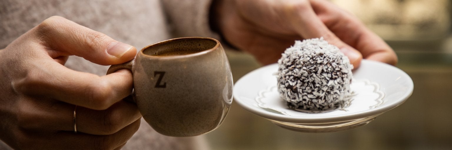 två händer som håller en espresso och en chokladboll