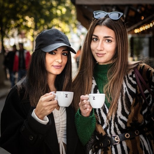 två kvinnor dricker espresso på gatan 