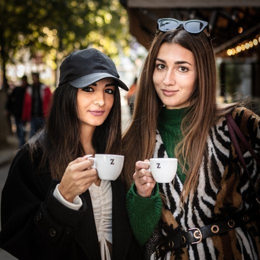två kvinnor dricker espresso på gatan