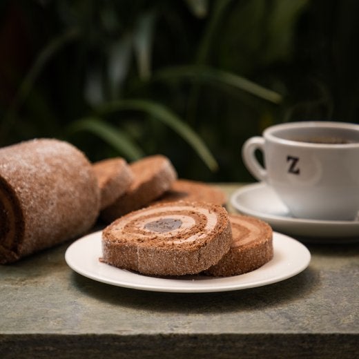 Chokladrulltårta med en kopp kaffe i bakgrunden 