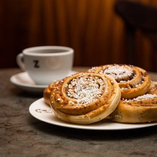 ett fat med kanelbullar och en kopp kaffe i bakgrunden 