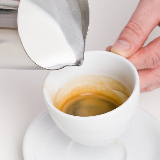 koppkaffe med mjölk som ska hällas i